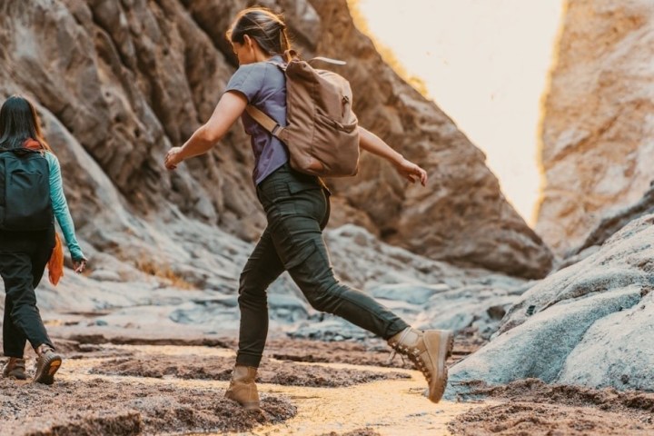 Two people hiking in a rocky canyon with backpacks, warm lighting.