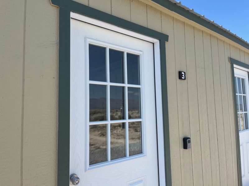 Exterior view of a beige building with a door numbered 3 and a window.