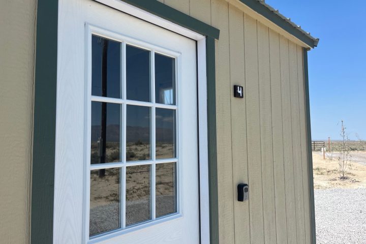 A small wooden building with a white door, glass panes, and the number 4.