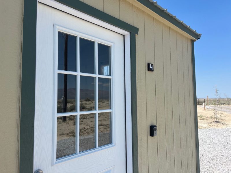 A small wooden building with a white door, glass panes, and the number 4.