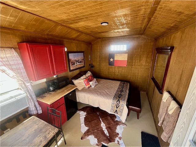 Cozy room with a bed, red kitchenette, Texas flag, cowhide rug, and rustic decor.