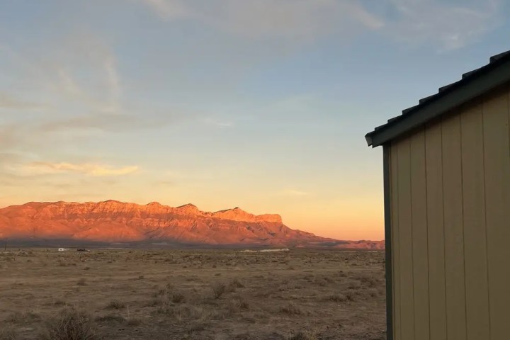 Distant mountains at sunset with a building in the foreground.