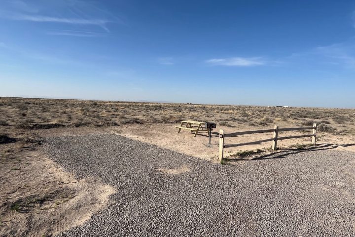 Upside-down landscape with a gravel path, clear sky, and wooden bench.